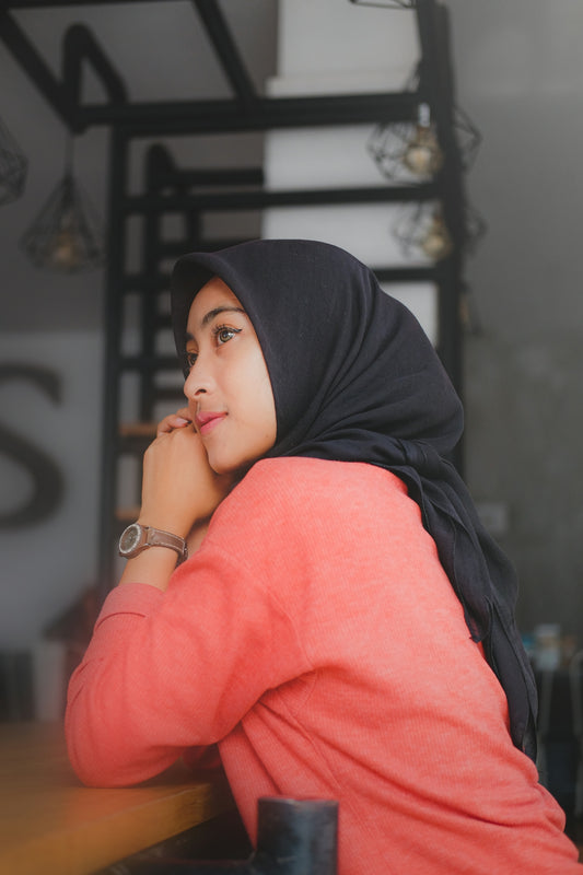 a woman sitting at a table with her hand on her chin