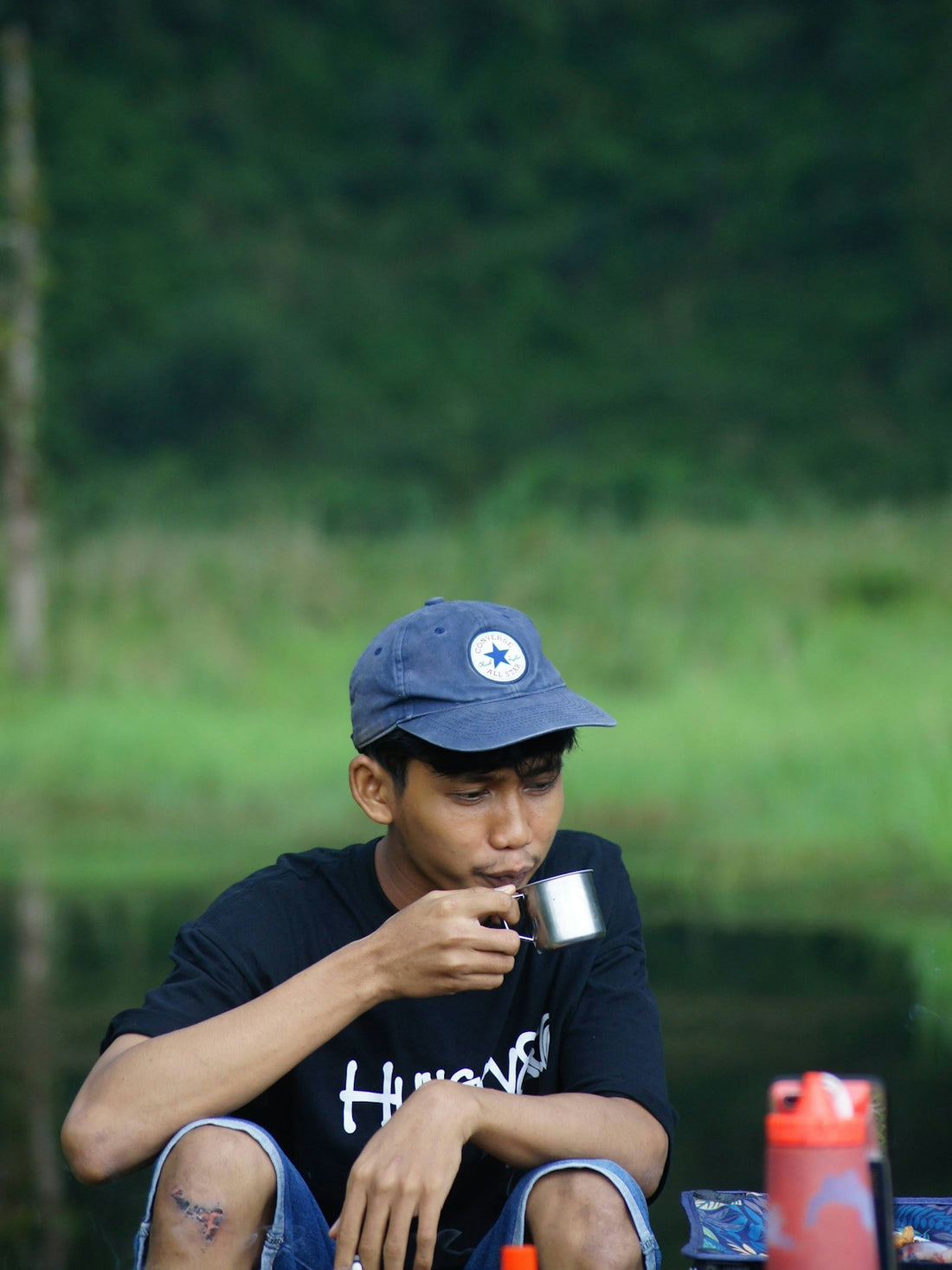 A man sitting on the ground next to a body of water