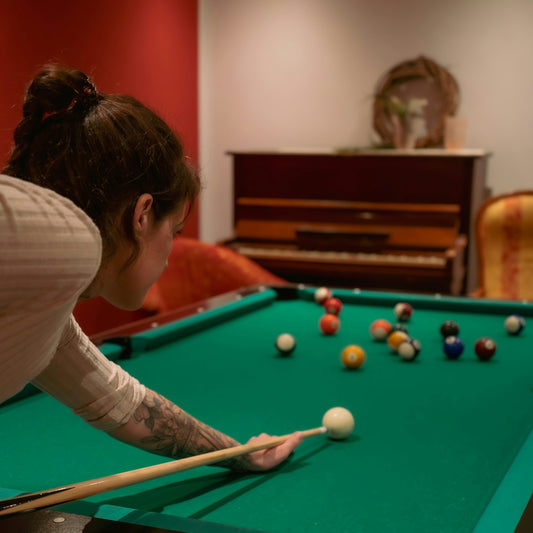A woman leaning over a pool table with a cue in her hand