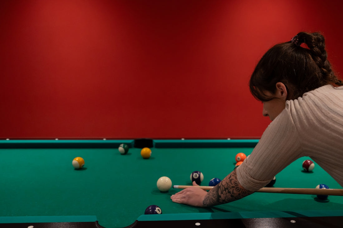 A woman leaning over a pool table with a cue in her hand
